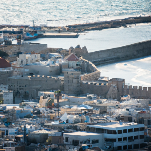 An aerial shot of the Old City of Akko, surrounded by the Mediterranean Sea, showcasing its ancient fortifications and harbor.